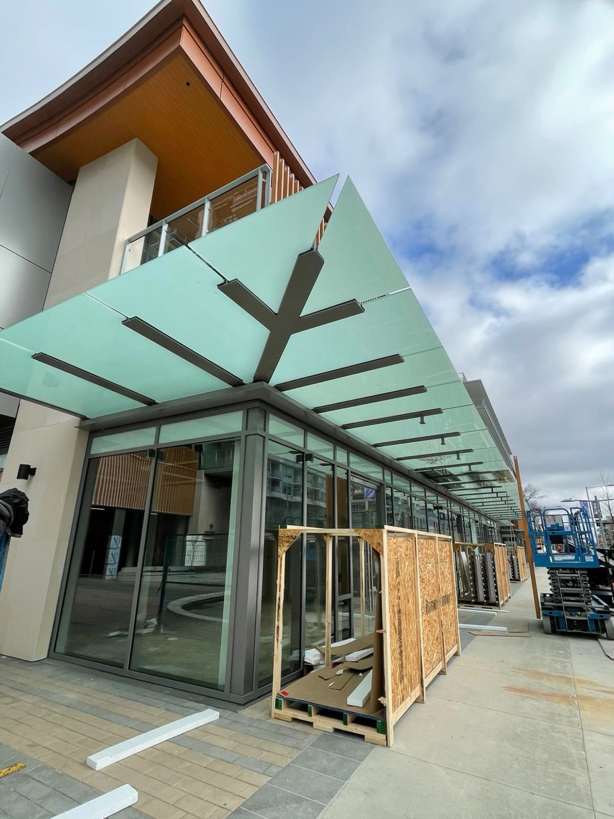 Frosted glass canopy on steel arms over a commercial storefront