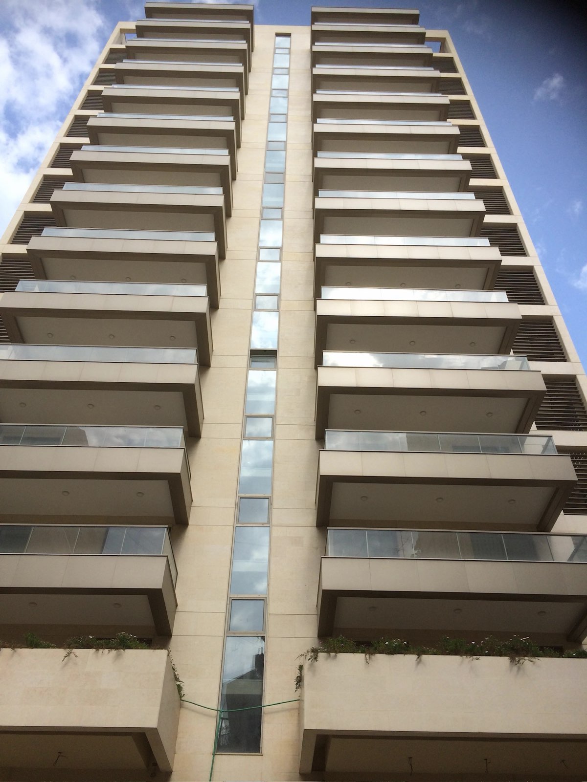 High-rise residential tower with glass balcony railings on every floor