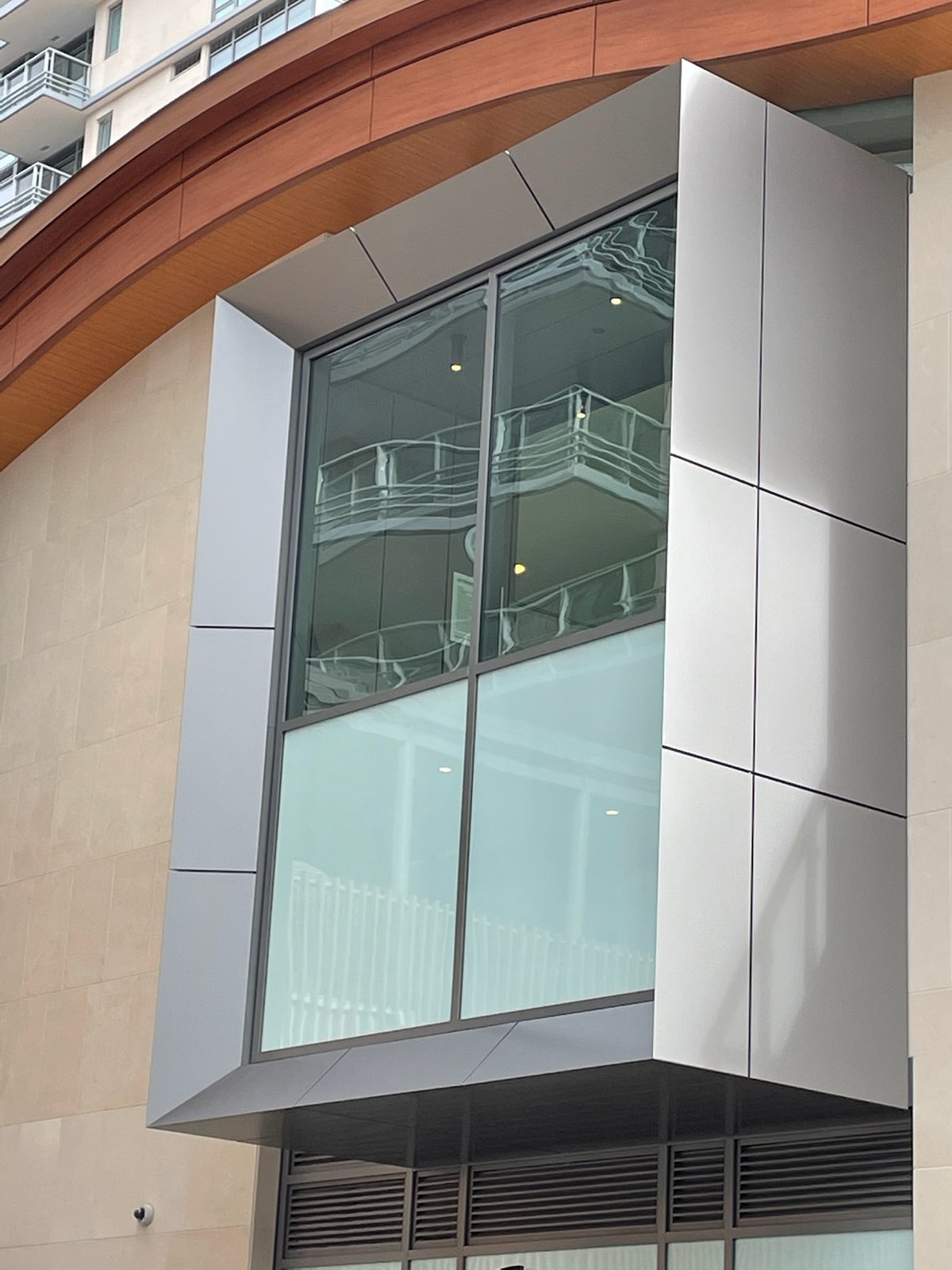 Two-storey glazed corner bay framed in metal panels under a curved fascia