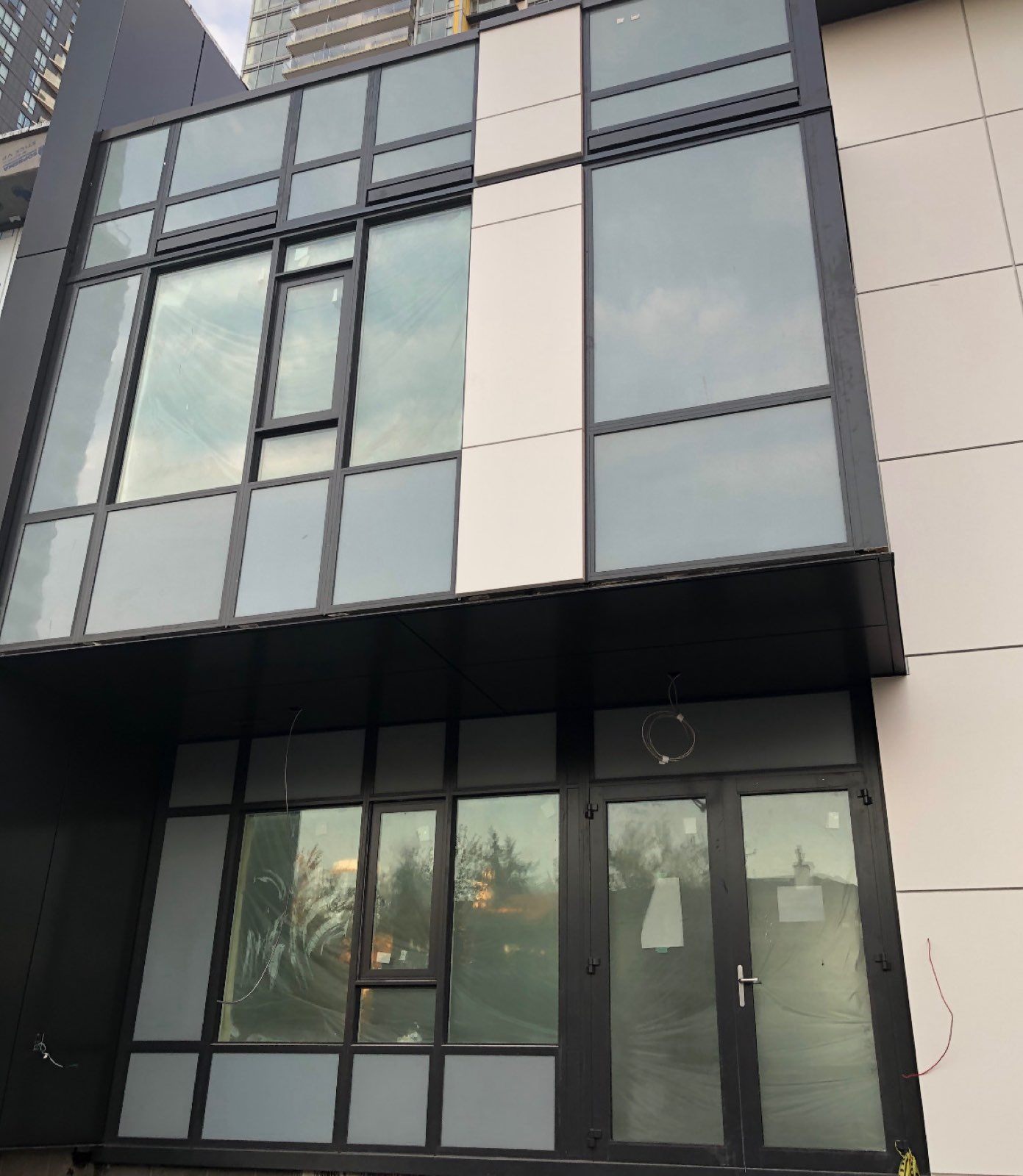 Black-framed windows and glass entrance doors on a light-panel facade