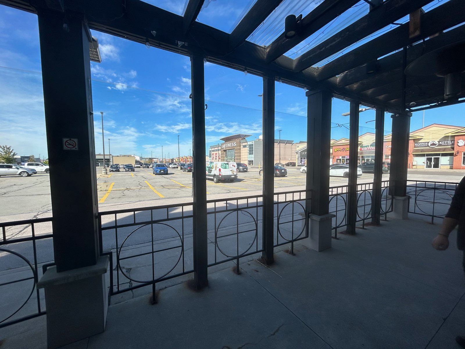 Covered walkway canopy on dark posts along a retail plaza