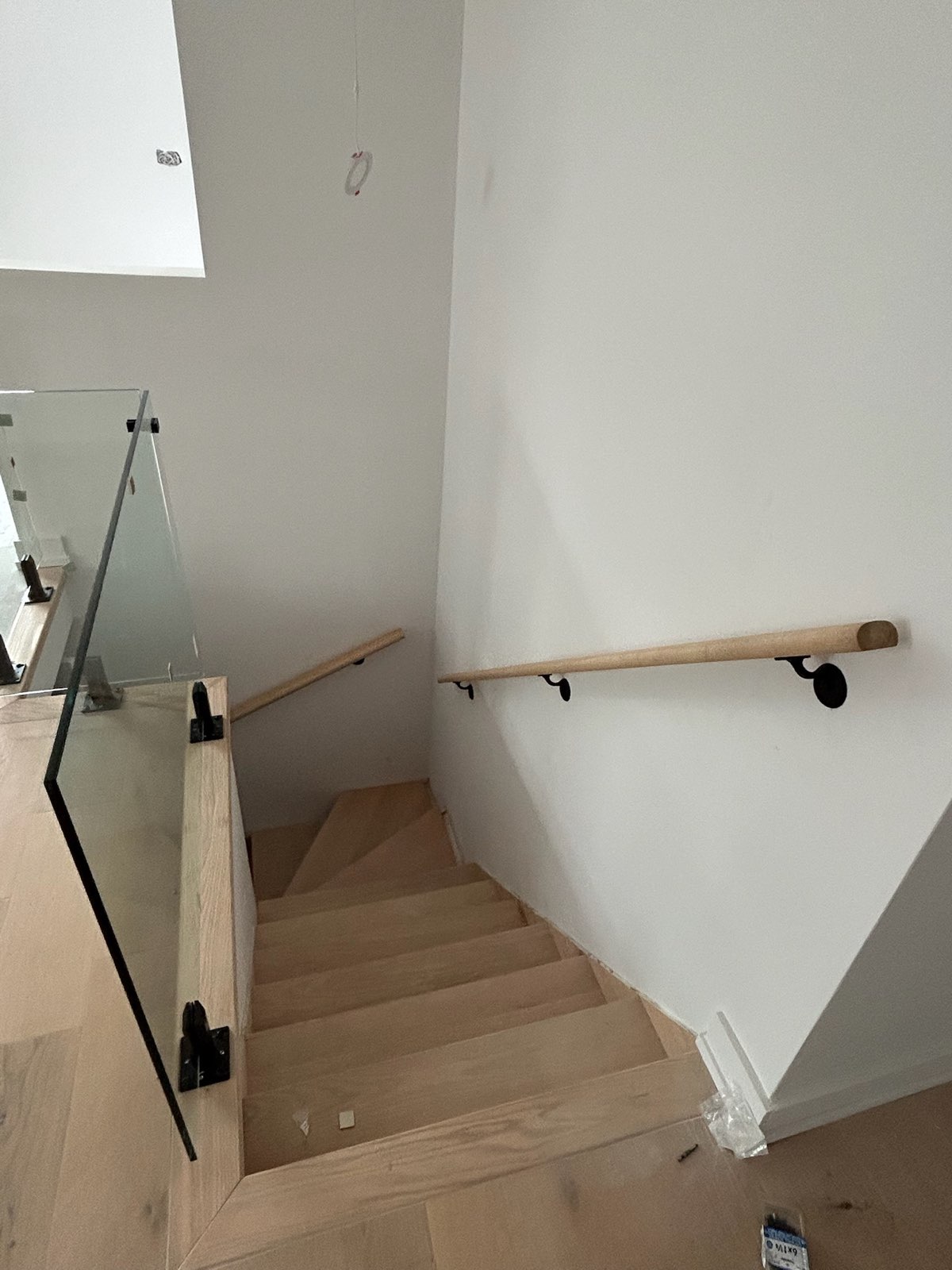 Frameless glass panel at a staircase with a wall-mounted wood handrail