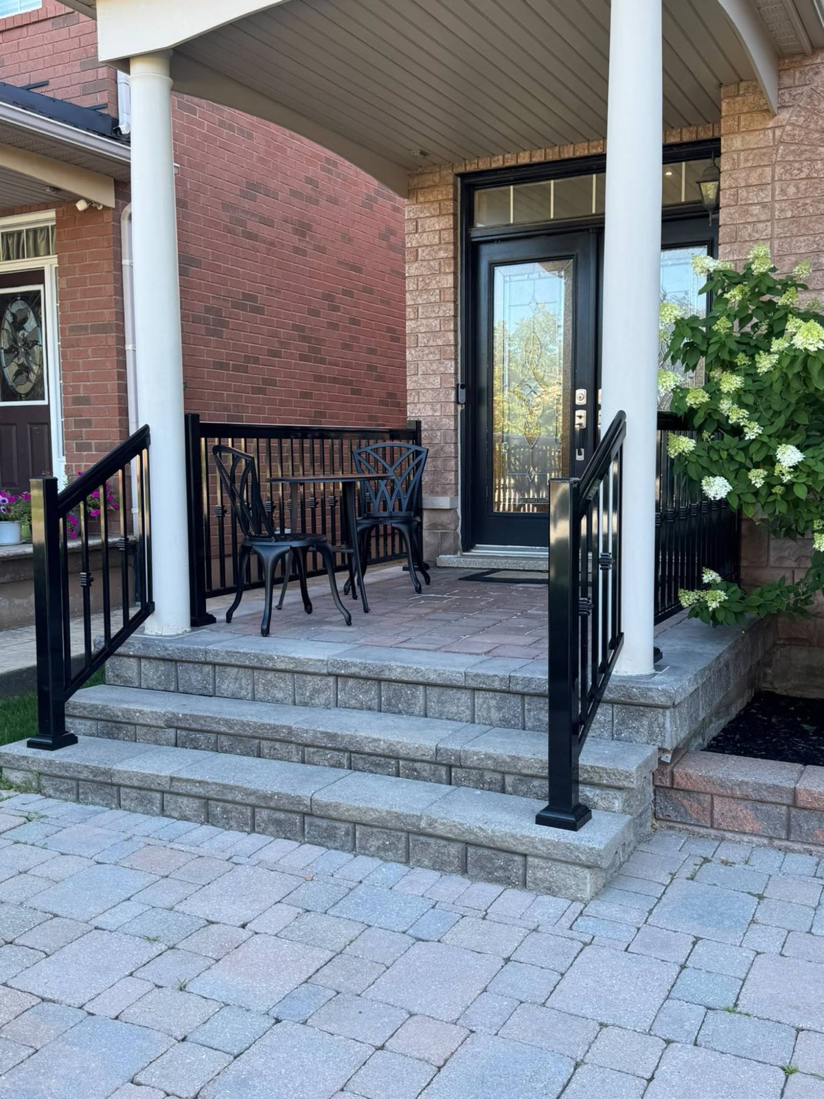 Black railings on the front porch and stone steps of a brick home