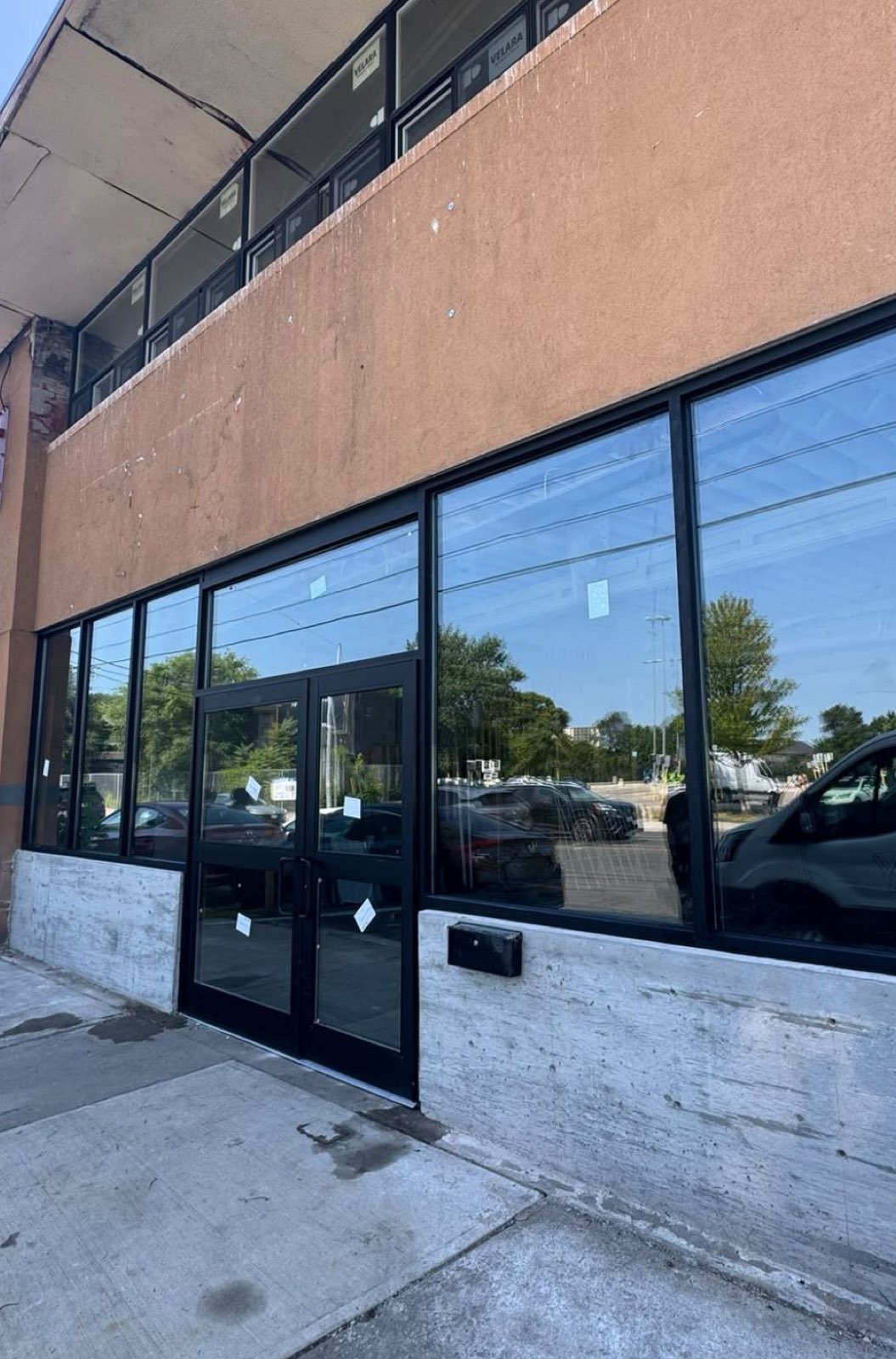 Black-framed storefront windows and double entry doors on a commercial building