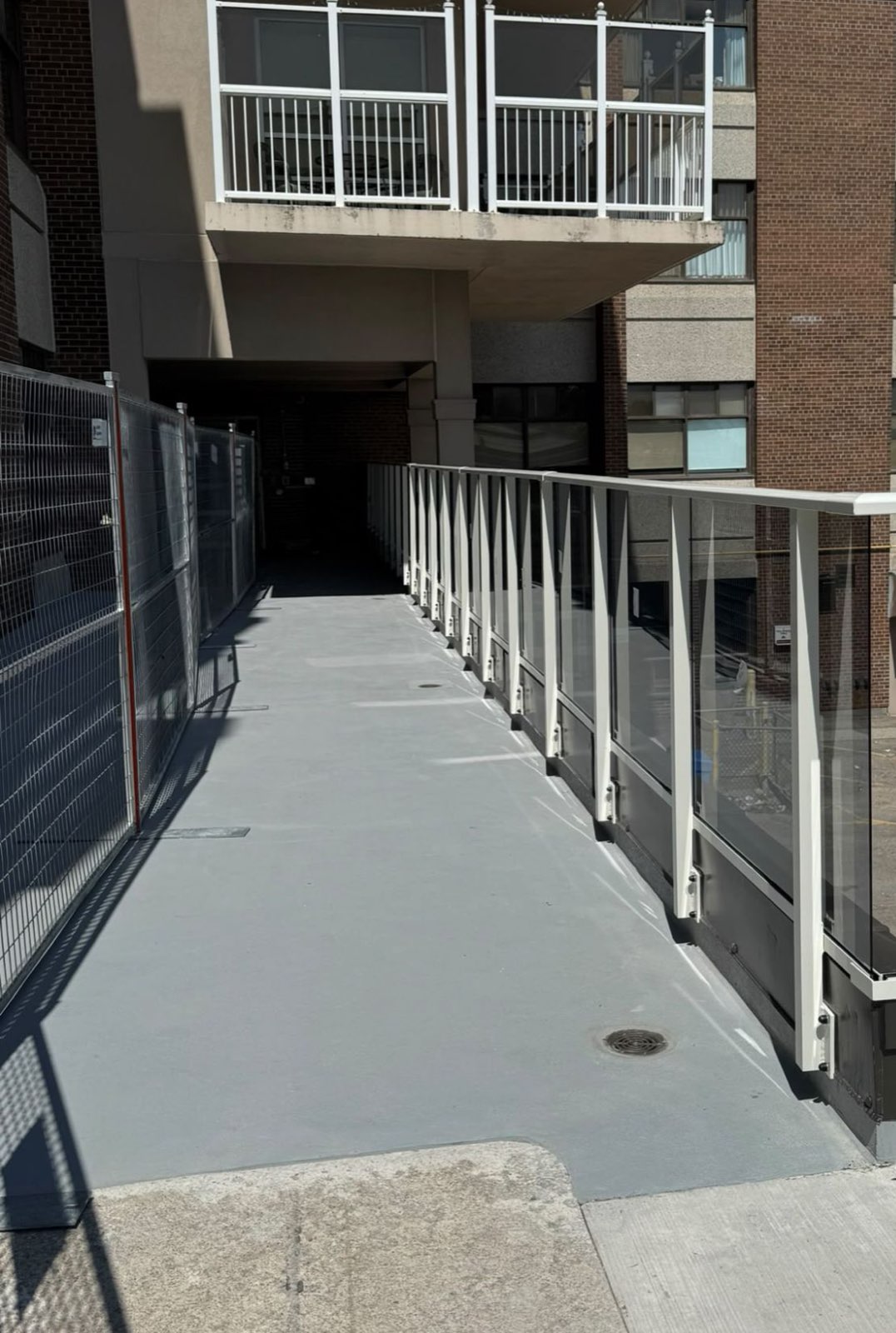 White railing with glass panels running along a sloped walkway