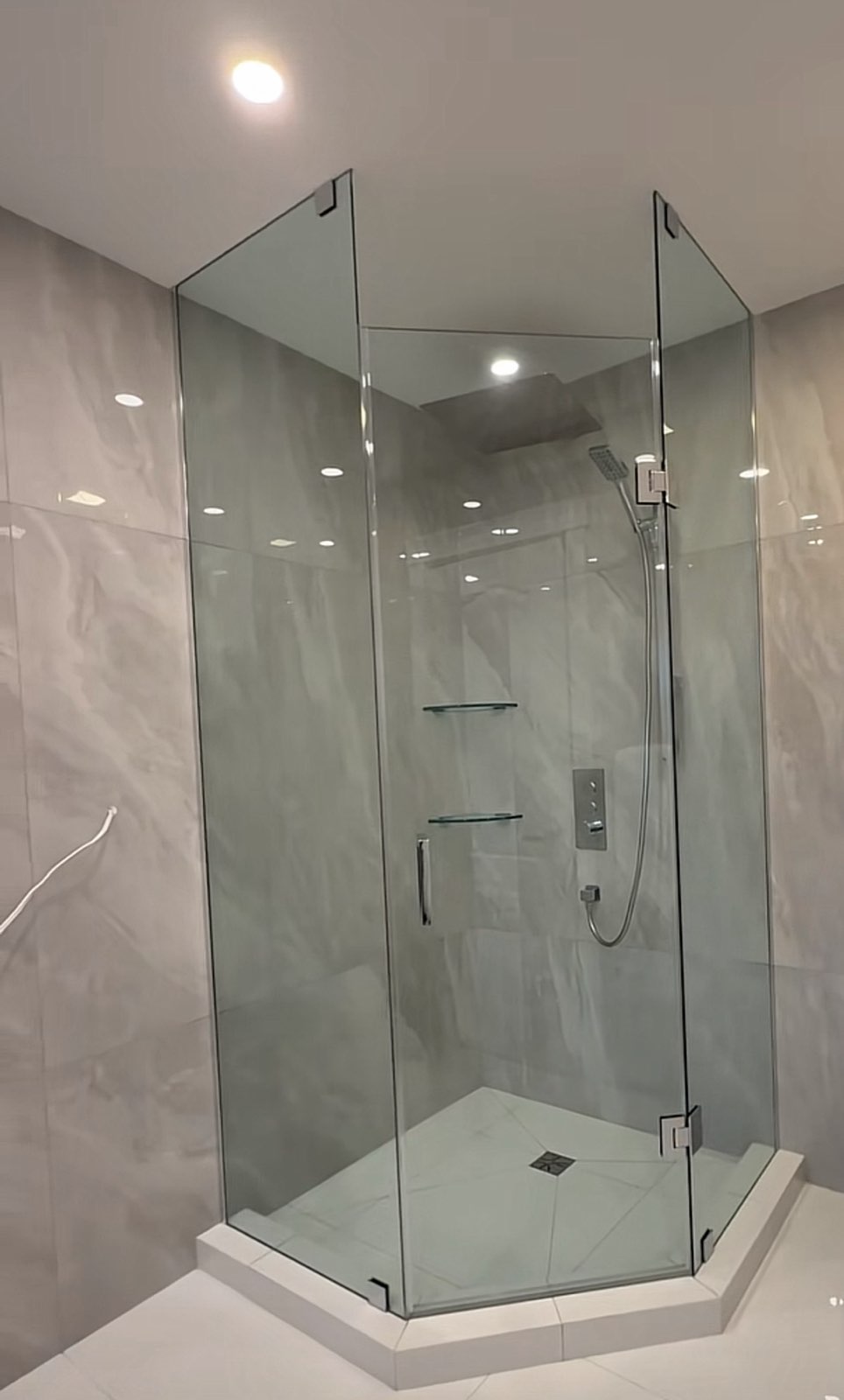 Three-panel neo-angle frameless glass shower in a white bathroom