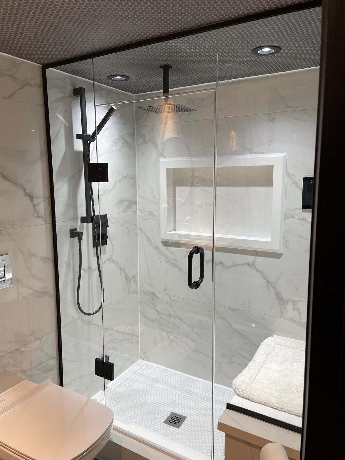 Frameless glass shower with black fixtures and a tiled niche