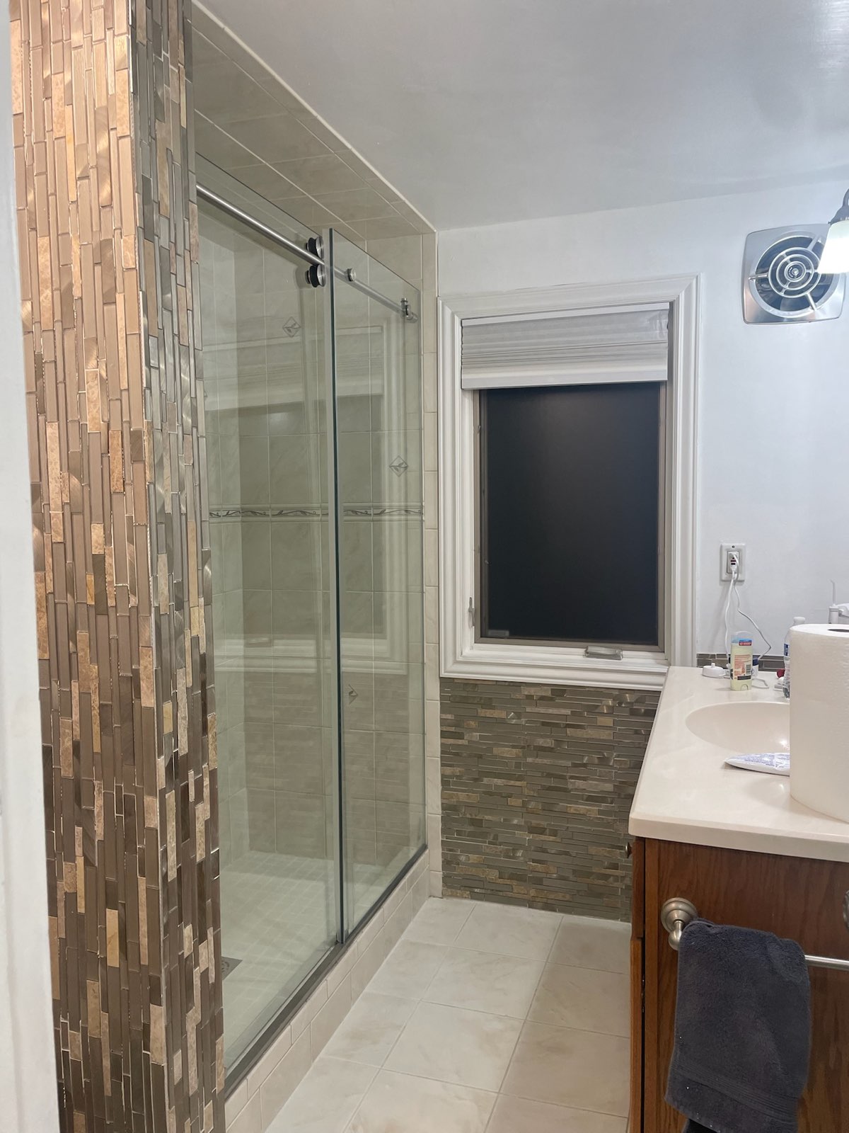 Frameless glass shower door beside a mosaic stone feature wall