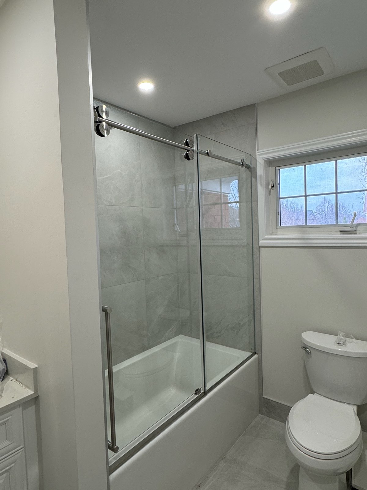 Frameless glass on a bathtub beside a window