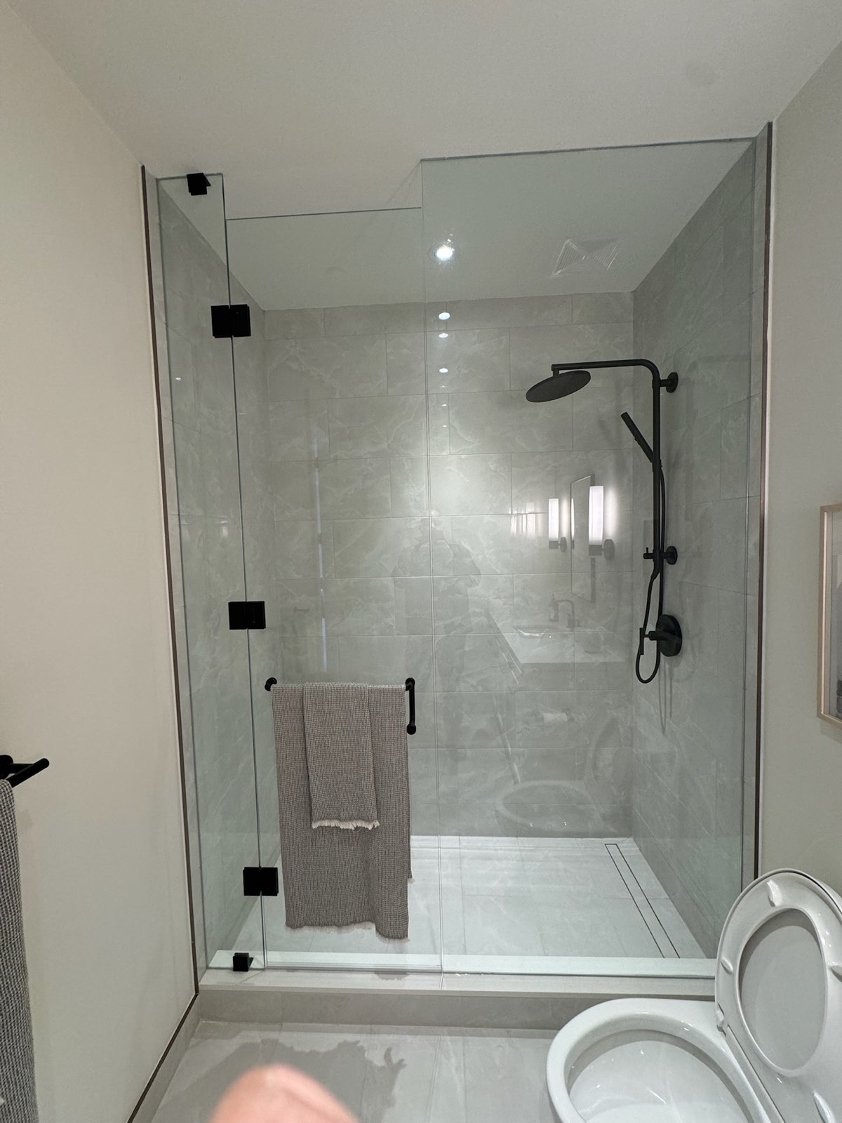 Frameless glass shower with a black shower column and hardware